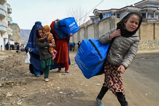 Afghans carry winter kits from UNICEF at Fayzabad in Badakhshan province on February 25, 2024. (Photo by Wakil Kohsar/AFP Photo)