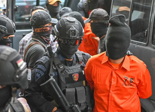 Indonesian police escort arrested terror suspects to a news conference in Jakarta on May 17, 2019. Indonesian police said on May 17, 2019 that they have arrested dozens of Islamic-State linked terror suspects, including some who planned to detonate bombs at political demonstrations when election results are announced next week. (Photo by Bay Ismoyo/AFP Photo)
