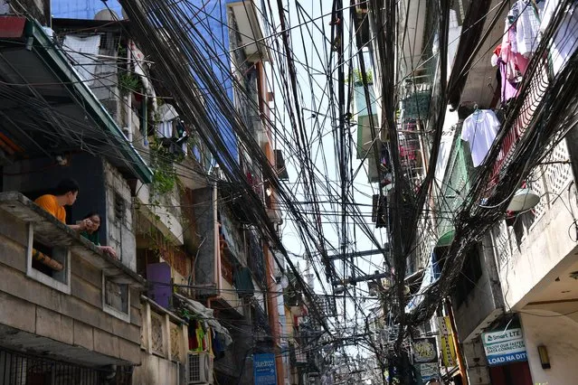 Residents stand on their house's balcony next to maze of cable and wires along a street in Manila on February 29, 2024. The Philippines economy grew slightly quicker than expected last year, data showed January 31, even as it was hit by high food prices and weakness in overseas markets. (Photo by Ted Aljibe/AFP Photo)