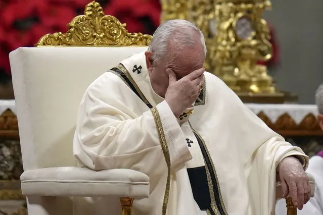 Pope Francis holds his head as he celebrates Christmas Eve Mass, at St. Peter's Basilica, at the Vatican, Friday December 24, 2021. Pope Francis celebrated Christmas Eve Mass before an estimated 1,500 people in St. Peter's Basilica on Friday, going ahead with the service despite the resurgence in COVID-19 cases that has prompted a new vaccine mandate for the Vatican City State. (Photo by Alessandra Tarantino/AP Photo)