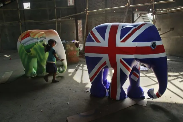 An Indian child plays near elephant statues being prepared to welcome the Duke and Duchess of Cambridge at the Centre for Wildlife Rehabilitation and Conservation in Panbari reserve forest near Kaziranga National Park east of Gauhati, northeastern Assam state, India, Tuesday, April 12, 2016. The British royal couple is visiting the wildlife park specifically to focus global attention on conservation. The 480-square-kilometer (185-square-mile) grassland park is home to the world's largest population of rare, one-horned rhinos as well as other endangered species, including swamp deer and the Hoolock gibbon. (Photo by Anupam Nath/AP Photo)