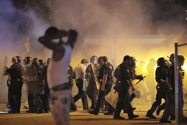 Police retreat under a cloud of tear gas as protesters disperse from the scene of a standoff after Frayser community residents took to the streets in anger against the shooting of a youth by U.S. Marshals earlier in the evening, Wednesday, June 12, 2019, in Memphis, Tenn. (Photo by Jim Weber/Daily Memphian via AP Photo)