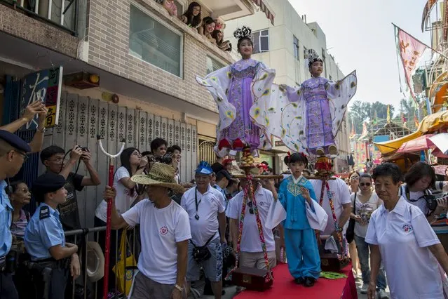 Girls, dressed in traditional Chinese costumes, stand above the crowd with the support of an elaborate rig of hidden metal rods as they take part in the Bun Festival parade at Hong Kong's Cheung Chau island, China May 25, 2015. (Photo by Tyrone Siu/Reuters)