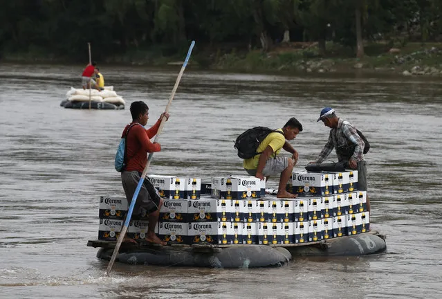 Raftsmen carry a load of Corona beer across the Suchiate River on an inner tube and plank raft, near Ciudad Hidalgo, Mexico, Monday, June 17, 2019, on the border with Guatemala. Along the Suchiate, merchants and politicians expressed concern that an immigration crackdown could impact the free flow of cross-border commerce on which communities on both sides depend. (Photo by Rebecca Blackwell/AP Photo)