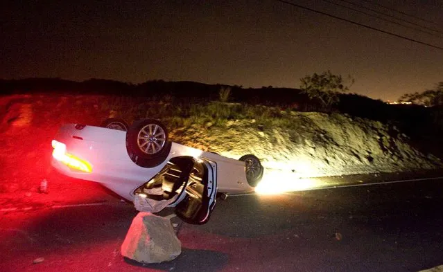 A car sits rolled over in the wake of Friday nights March 28, 2014 earthquake on Carbon Canyon Road in Brea, Calif., near Olinda Village. (Photo by Rod Veal/AP Photo/The Orange County Register)