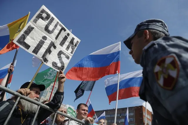 People with Russian and various political party flags stand in front of police line during a protest in Moscow, Russia, Saturday, July 20, 2019. Masses of people gathered in central Moscow to demand that opposition candidates be included on ballots for an upcoming city parliament election in September. (Photo by Pavel Golovkin/AP Photo)