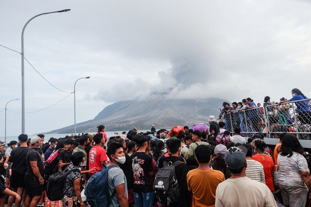 Evacuees board an Indonesian naval vessel on Tagulandang Island in Sitaro, North Sulawesi on May 1, 2024, as Mount Ruang volcano spews smoke in the background. Eruptions at a remote Indonesian volcano forced more than half a dozen airports to close with ash spreading as far as Malaysia, officials said on May 1, while authorities rushed to evacuate thousands due to tsunami fears. (Photo by Ronny Adolof Buol/AFP Photo)