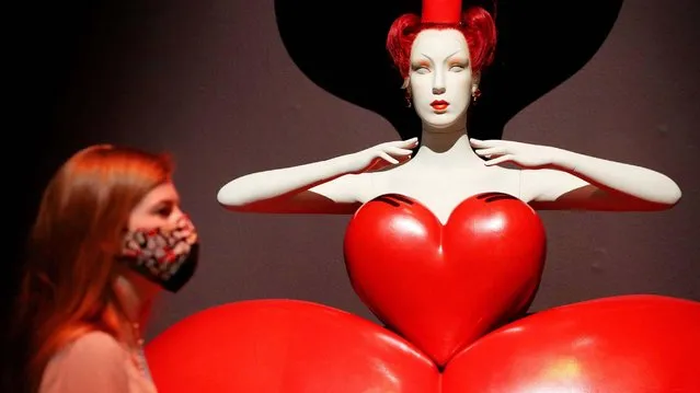 A Victoria and Albert Museum employee stands before a costume for the Queen of Hearts by Bob Crowley on display at the “Alice: Curiouser and Curiouser” exhibition at the Victoria and Albert Museum in London on Tuesday, May 18, 2021. (Photo by Jonathan Brady/PA Images via Getty Images)
