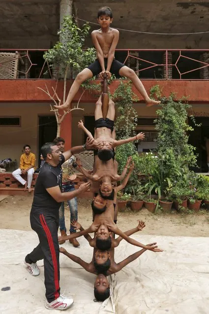 An instructor helps boys to balance as they practice “Malkhamb” (traditional Indian gymnastics) during a rehearsal for the upcoming annual Rath Yatra, or chariot procession, in Ahmedabad, India, July 5, 2015. (Photo by Amit Dave/Reuters)