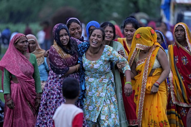 Bharti Kumari, centre, and Sonam, centre right behind Kumari, weep as the body of their mother Savitri Devi, 50, who died during a stampede, is carried for cremation in Ramnagar, in the northern Indian state of Uttar Pradesh, Wednesday, July 3, 2024. Devi was among more than 120 people who died in a stampede last week at a religious festival in northern India, as the faithful surged toward the preacher and chaos ensued among the attendees. (Photo by Rajesh Kumar Singh/AP Photo)