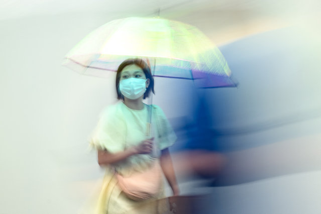 A woman uses an umbrella to shelter from the rain while walking on a street in Tokyo's Shinjuku district on June 18, 2024. (Photo by Philip Fong/AFP Photo)