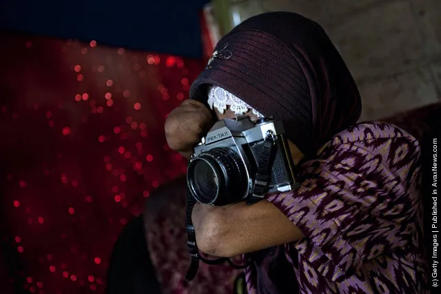 Armless professional photographer Rusidah, 44, takes a photograph as she carries out camera maintenance