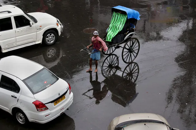 An Indian rickshaw puller is reflected on a wet street during a monsoon shower in Calcutta, India, 20 July 2015. The Indian monsoon takes place between May and September. (Photo by Piyal Adhikary/EPA)