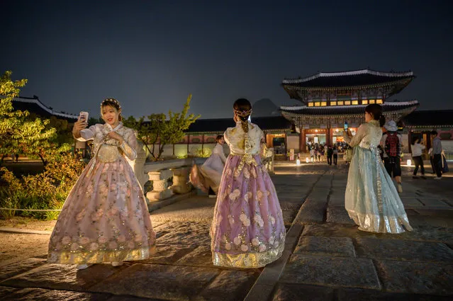 In a photo taken on October 4, 2019, visitors wearing traditional Korean hanbok dresses pose for photos during a night opening at Gyeongbokgung palace in central Seoul. (Photo by Ed Jones/AFP Photo)