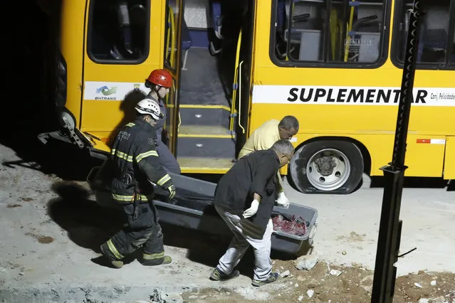 Rescue personel carry a body that was pulled from the bus behind them, near a bridge after it collapsed in Belo Horizonte, Brazil, Thursday, July 3, 2014. The overpass under construction collapsed Thursday in the Brazilian World Cup host city. The incident took place on a main avenue, the expansion of which was part of the World Cup infrastructure plan but, like most urban mobility projects related to the Cup, was not finished on time for the event. (Photo by Victor R. Caivano/AP Photo)