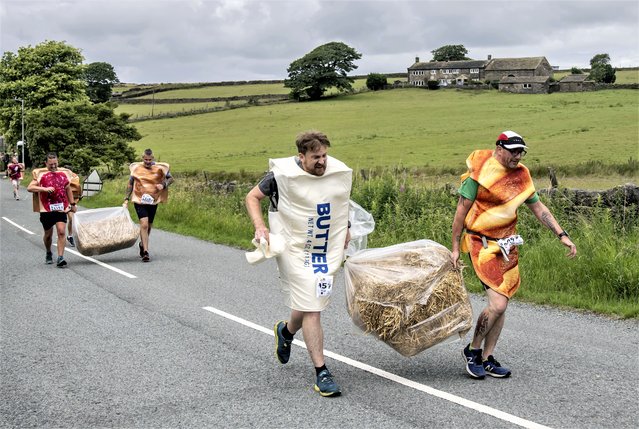 Competitors takes part on the Oxenhope Straw Race in West Yorkshire, UK, a 2.5 miles race in fancy dress while carrying a 20kg bale of straw along the route on Sunday, July 2, 2023. The race takes place every summer in the Pennine village of Oxenhope, and was started by two men who had a bet about who could win a racing from one pub to the next carrying a bale of straw. (Photo by Danny Lawson/PA Images via Getty Images)