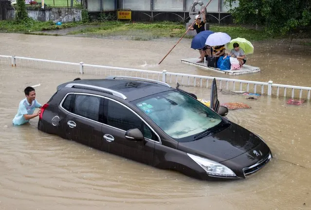 A trapped car is pushed along a flooded street after typhoon Soudelor hit Fuzhou, Fujian province, China, August 9, 2015. The typhoon battered China's east coast on Sunday, killing eight people and forcing authorities to cancel hundreds of flights and evacuate more than 163,000 people. (Photo by Reuters/Stringer)