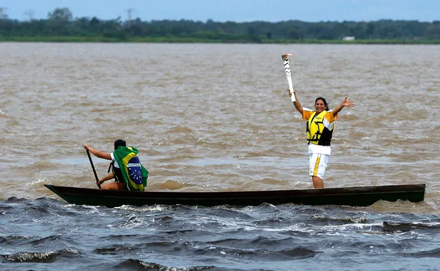 Brazilian canoeist Raimunda Araujo Freitas takes part in the Olympic Flame torch relay at the confluence point between the Negro river and the Solimoes river, in Manaus, Amazonas state, Brazil, June 20, 2016. (Photo by Bruno Kelly/Reuters)