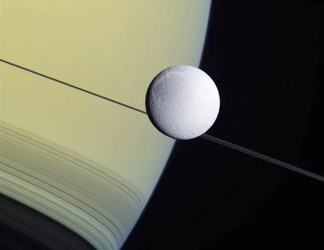 This wide-angle view from NASA's Cassini probe shows the Saturnian moon Dione set against the giant planet's disk and rings on May 2 2012