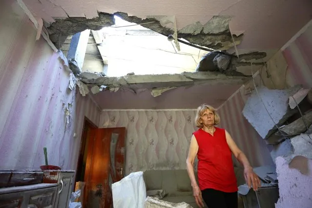 A resident of the eastern Ukrainian city of Donetsk walks through her apartment building that was destroyed as a result of night shelling between Ukrainian forces and pro-Russian separatists on June 24, 2016. (Photo by Aleksey Filippov/AFP Photo)