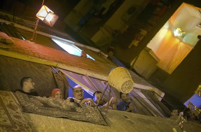 In this Monday, June 12, 2017 photo, residents of the Ard Besary district peer out their balconies to watch  Dalal Abdel-Qader, known as Hajjaj Dalal, a 43-year-old “mesaharati”, or dawn caller, as she wakes people up for a meal before sunrise, during the Islamic holy month of Ramadan, in the Ard Besary district in Cairo, Egypt. (Photo by Amr Nabil/AP Photo)