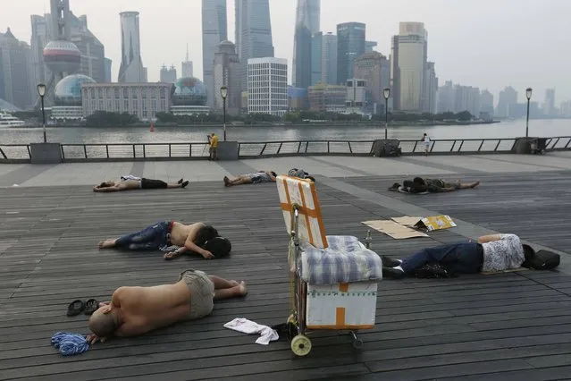 This photo taken on July 25, 2017 shows people sleeping on the waterfront bund to keep cool in Shanghai. Parts of China including Shanghai have seen record temperatures in recent weeks, in what has been a torrid summer so far for much of the country, while large areas of south-central China have endured raging floods from torrential rain. (Photo by AFP Photo/Stringer)