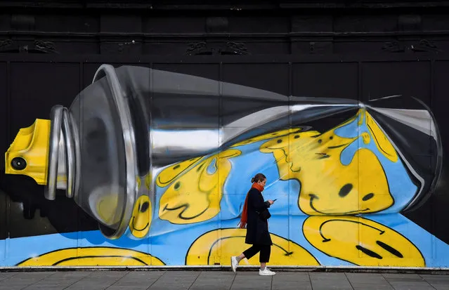 A woman views her phone as she walks past street art on a wall in London, Britain, December 18, 2019. (Photo by Toby Melville/Reuters)