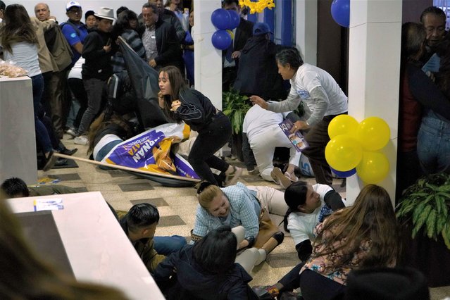 People take cover after shots were fired at the end of a political rally in Quito, Ecuador on Wednesday, August 9, 2023. Presidential candidate Fernando Villavicencio was assassinated as he was leaving the rally. Villavicencio, a legislator in the National Assembly, had been outspoken about corruption and the violence caused by drug trafficking in the country. He was 59 years old. (Photo by Juan Ruiz Condor/API via AP Photo)