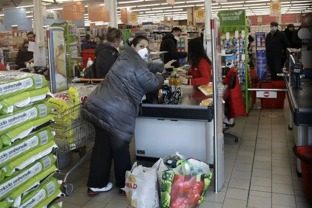 Clients wear sanitary mask in a supermarket in Casalpusterlengo, Italy, Sunday, February 23, 2020. A dozen Italian towns saw daily life disrupted after the deaths of two people infected with the virus from China and a pair of case clusters without direct links to the outbreak abroad. A rapid spike in infections prompted authorities in the northern Lombardy and Veneto regions to close schools, businesses and restaurants and to cancel sporting events and Masses. (Photo by Luca Bruno/AP Photo)