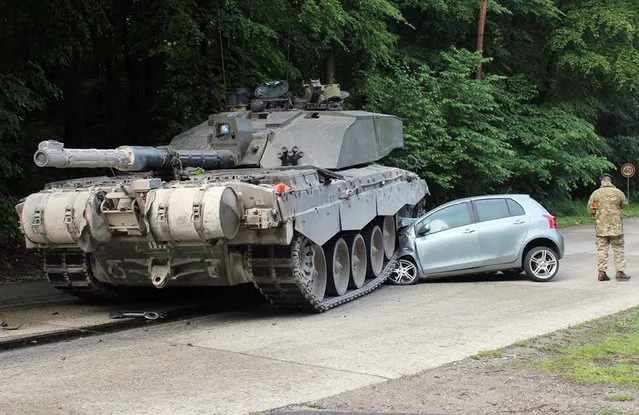 A handout photo provided by the Police department in Lippe on 01 June 2015 of a British “Challenger 2” tank after it rolled over a car's front in Lippe, Germany, 01 June 2015. Police reported that a 18-year old female driving beginner from Detmold apparently overlooked a convoy of tanks when she turned left onto the Panzeringstrasse (lit. Tank Ring Road). The driver of the convoy'e leading tank, a 24-year old British national, was not able to stop his vehicle fast enough, hit the car and overran the vehicle's front. The young female car driver remained unhurt. The exclusive damage to the car was estimated at about 12,000 euro. (Photo by EPA/Polizei Lippe)