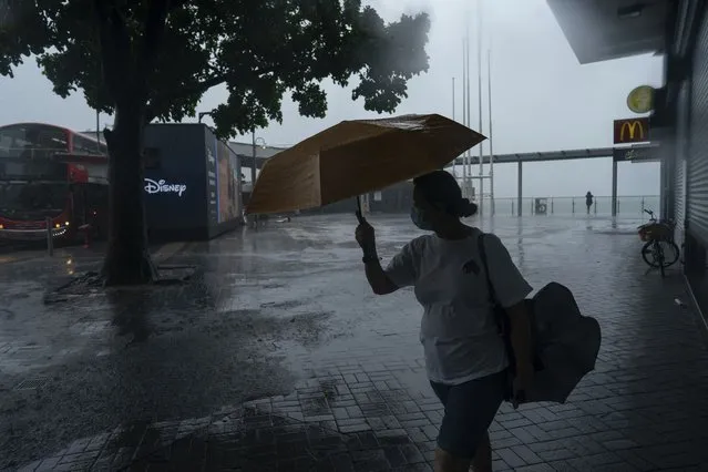 A woman holds an umbrella under strong wind near the promenade of Victoria Habour as tropical storm Ma-on passes Hong Kong, Thursday, August 25, 2022. (Photo by Anthony Kwan/AP Photo)
