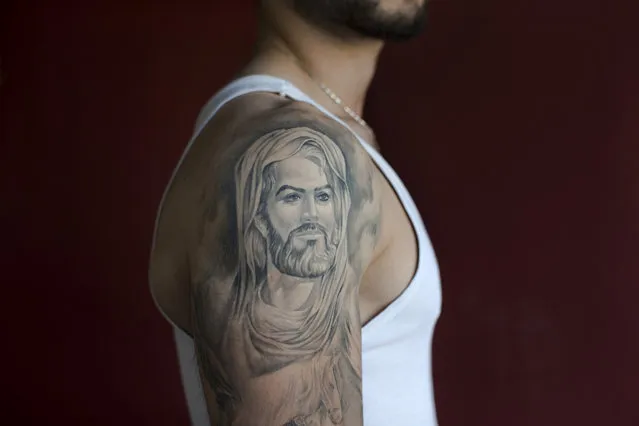 In this Tuesday, May 31, 2016 photo, Ali, 22, poses for a photo showing off his tattoo of Shiite Muslims' first Imam Ali, in the southern suburb of Beirut, Lebanon. (Photo by Hassan Ammar/AP Photo)