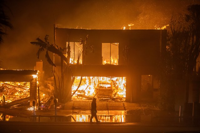 A firefighter watches the flames from the Palisades Fire burning homes on the Pacific Coast Highway amid a powerful windstorm on January 8, 2025 in Los Angeles, California.  The fast-moving wildfire has grown to more than 2900-acres and is threatening homes in the coastal neighborhood amid intense Santa Ana Winds and dry conditions in Southern California. (Photo by Apu Gomes/Getty Images)