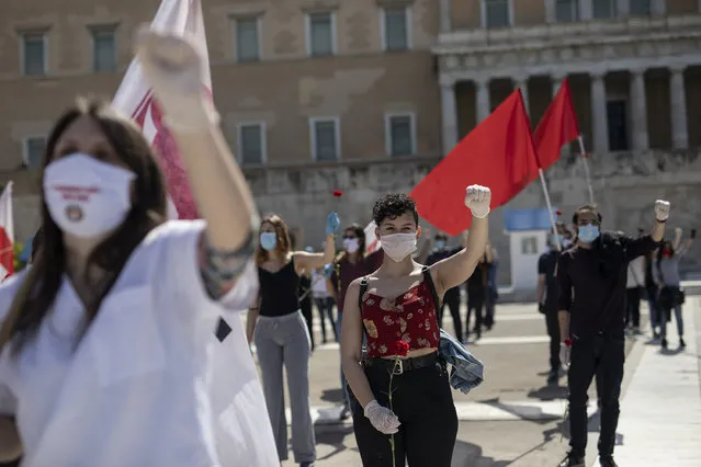 Protesters from the communist party-affiliated PAME union wearing masks to protect against coronavirus, march during a May Day rally outside the Greek Parliament, in Athens, on Friday, May 1, 2020. Hundreds of protesters gathered in central Athens and the northern Greek city of Thessaloniki to mark May Day, despite appeals from the government for May Day marches and commemorations to be postponed until next Saturday, when some lockdown measures will have been lifted. (Photo by Petros Giannakouris/AP Photo)