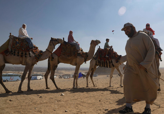 A camel driver takes tourists for a ride at the Pyramids Plateau in Giza, on the outskirts of Cairo, Egypt, on October 29, 2024. (Photo by Amr Abdallah Dalsh/Reuters)