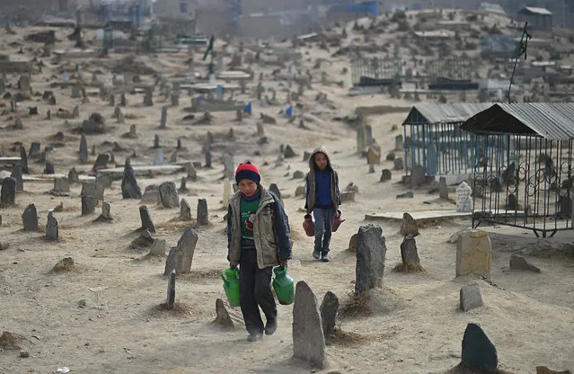 Afghan children who work as water vendors search for customers at the Kart-e-Sakhi cemetery in Kabul on January 12, 2015. Thousands of victims of the country's civil war which raged from 1992 to 1996 are buried in cemetries across the Afghan capital. (Photo by Shah Marai/AFP Photo)
