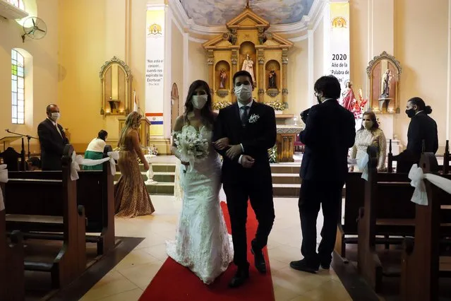 Bride Jazmin Sanabria and her groom Joel Adorno, wearing protective face masks amid the new coronavirus pandemic, walk down the aisle in the first wedding ceremony since 101 days of quarantine at the Virgen del Rosario church, in Luque, Paraguay, Saturday, June 20, 2020. The government is easing restrictive measures, authorizing the opening of some stores, restaurants and churches that had been closed since March 10, as part of a plan coined, “Intelligent Quarantine”. (Photo by Jorge Saenz/AP Photo)