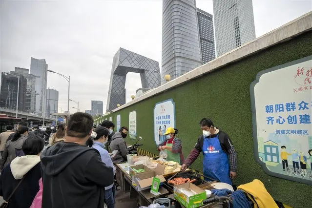 Street vendors wearing face masks make takeaway food for commuters at a cart in the central business district in Beijing, Friday, October 28, 2022. (Photo by Mark Schiefelbein/AP Photo)