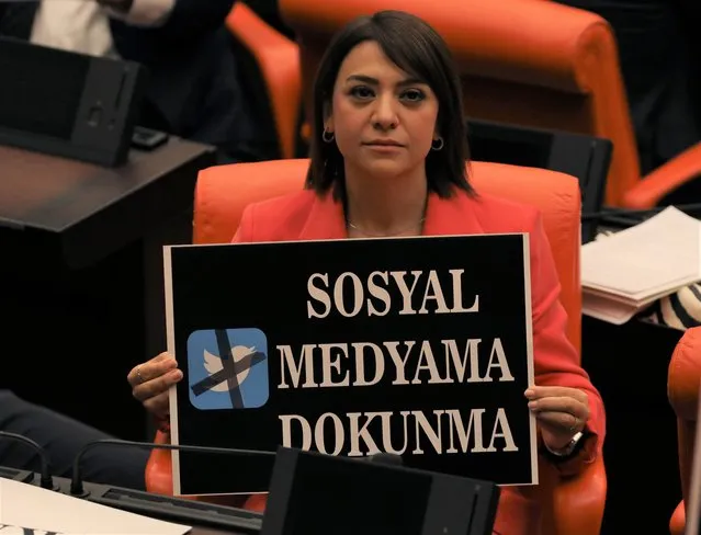 A lawmaker from the main opposition Republican People's Party holds up a placardthat reads “Don't touch my social media” in protest at the parliament, in Ankara, Turkey, Tuesday, October 11, 2022. Turkey's parliament continued to debate a highly controversial draft law Tuesday in Ankara. The government says the bill is aimed at combating fake news and disinformation but critics denounce it as yet another attempt to stifle freedom of expression. (Photo by Burhan Ozbilici/AP Photo)