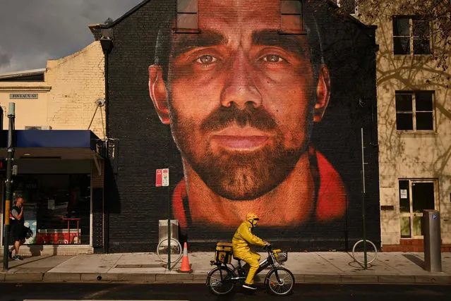 A cyclist rides past a giant mural of Adam Goodes, one of Australia's most high-profile indigenous sportsmen, in Sydney on June 29, 2020. Australia's most popular spectator sport has long grappled with racial vilification, and the recent “Black Lives Matter” protest movement has again shone the spotlight on a scourge that still plagues Aussie Rules. (Photo by Peter Parks/AFP Photo)