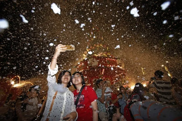 Women take 'selfies' in a fake snowfall of foam at a Christmas tree outside a mall near Orchard Road in Singapore December 18, 2014. (Photo by Edgar Su/Reuters)
