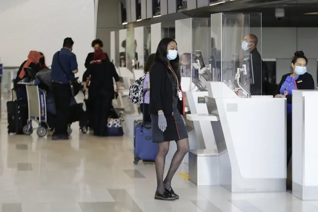 Ticket agents wear protective masks during the coronavirus pandemic while helping travelers at LaGuardia Airport, Wednesday, July 15, 2020, in New York. (Photo by Frank Franklin II/AP Photo)