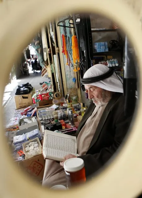 A Palestinian man is reflected in a mirror as he reads the Koran, Islam's holy book, in front of his shop in the old part of the West Bank city of Hebron, 22 June 2016. Muslims around the world celebrate the holy month of Ramadan by praying during the night time and abstaining from eating and drinking during the period between sunrise and sunset. Ramadan is the ninth month in the Islamic calendar and it is believed that the Koran's first verse was revealed during its last 10 nights. (Photo by Abed Al Hashlamoun/EPA)