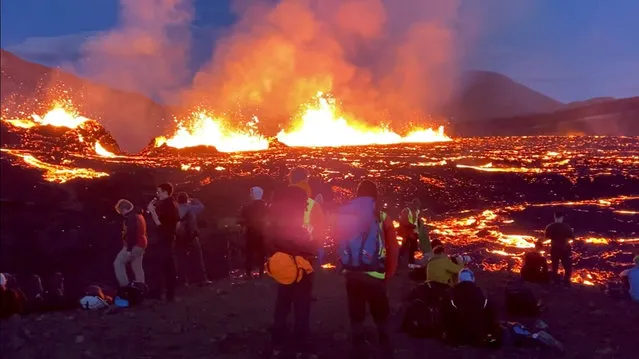 People look on as Fagradalsfjall volcano erupts near Reykjavik, Iceland on August 3, 2022 in this screen grab obtained from a social media video. (Photo by @alberttourguideiceland/Instagram via Reuters)