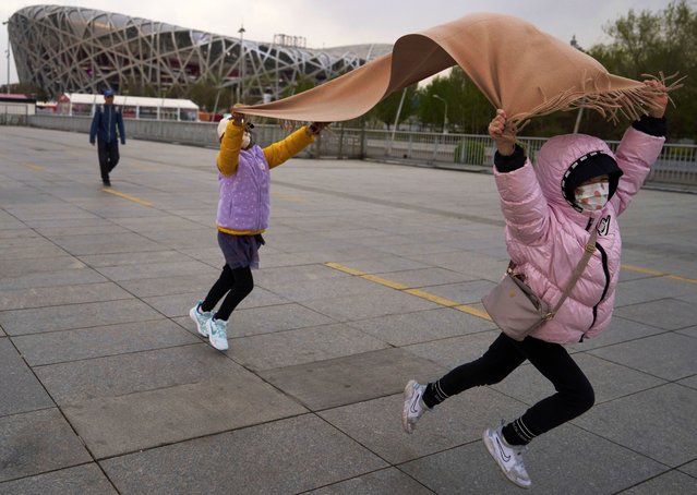 Children play with a scarf in strong winds near the iconic Bird's Nest National Stadium in Beijing, China, Saturday, April 12, 2025. (Photo by Ng Han Guan/AP Photo)
