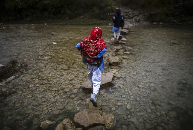 A girl crosses a stream as she walks to school in Margalla Hills, Islamabad, October 24, 2014. (Photo by Zohra Bensemra/Reuters)