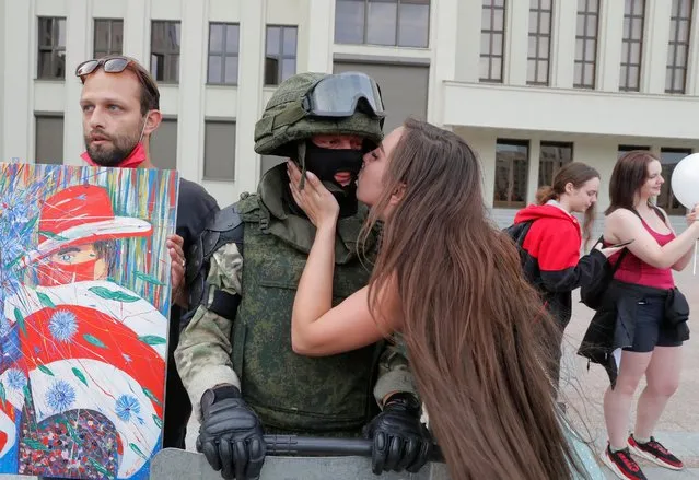 A participant kisses a member of Belarusian Interior Ministry troops, who stands guard during an opposition demonstration to protest against police violence and to reject the presidential election results near the Government House in Independence Square in Minsk, Belarus on August 14, 2020. (Photo by Vasily Fedosenko/Reuters)