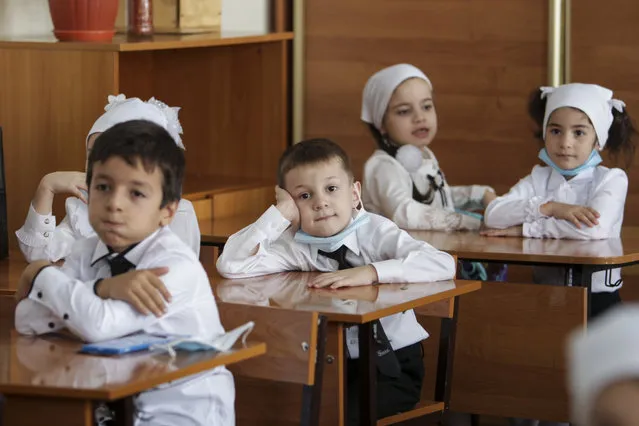 Pupils wearing face masks to protect against coronavirus sit in a classroom during a ceremony marking the start of classes at a school as part of the traditional opening of the school year known as “Day of Knowledge” in Grozny, Russia, Tuesday, September 1, 2020. Across the country, schools start their usually festive opening day on Sept. 1. (Photo by Musa Sadulayev/AP Photo)