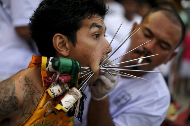 A devotee of the Chinese Samkong Shrine reacts while being pierced with spikes through his cheeks before a procession celebrating the annual vegetarian festival in Phuket, Thailand October 16, 2015. (Photo by Jorge Silva/Reuters)
