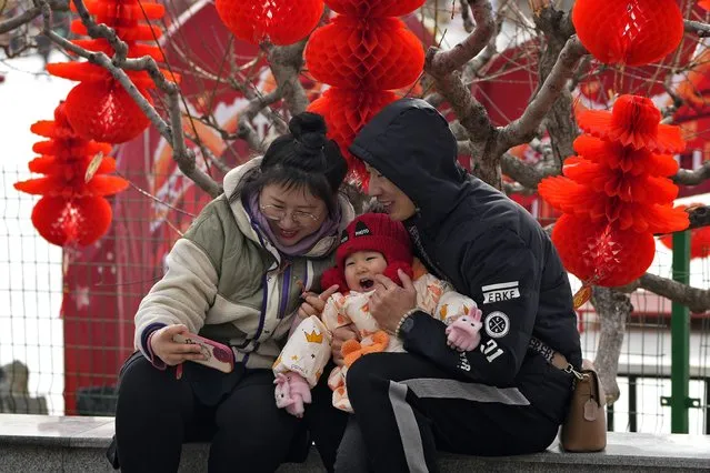 A couple take a selfie with their toddler in front of Lunar New Year decorations at a public park in Beijing, Thursday, January 19, 2023. (Photo by Andy Wong/AP Photo)